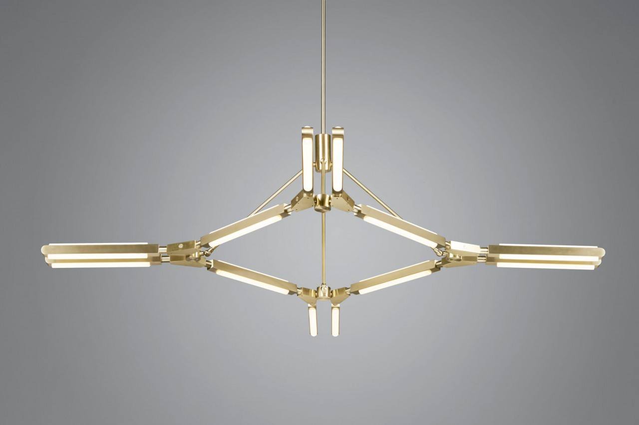 Three quarter view of an illuminated Pris Major chandelier with satin brass metal components.