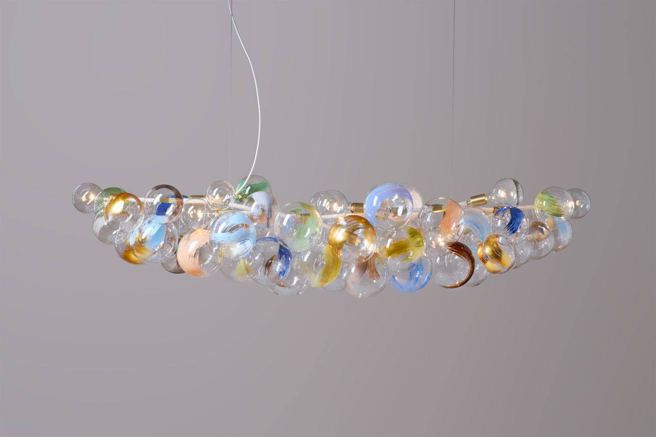An illuminated bubble chandelier with satin brass hardware, cotton cord detailing and colorful brush strokes on its glass globes.